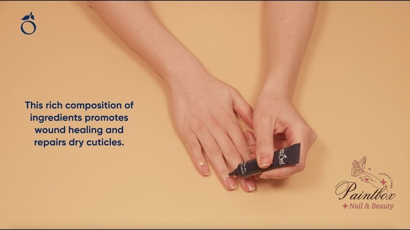 A close-up shot of a hand with a woman applying cuticle cream, showing how to use cuticle cream for nail care.